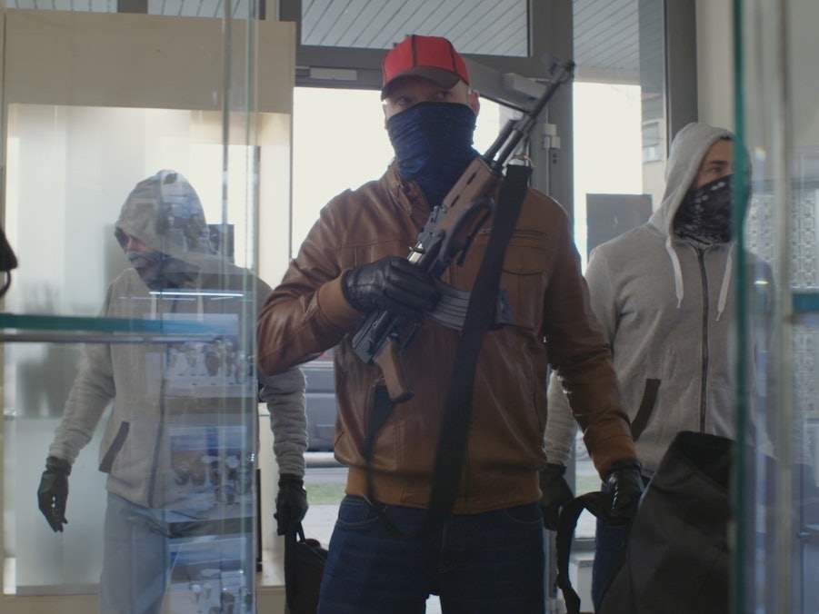 Drei vermummte Männer betreten ein Juweliergeschäft, einer ist mit einem Sturmgewehr bewaffnet.