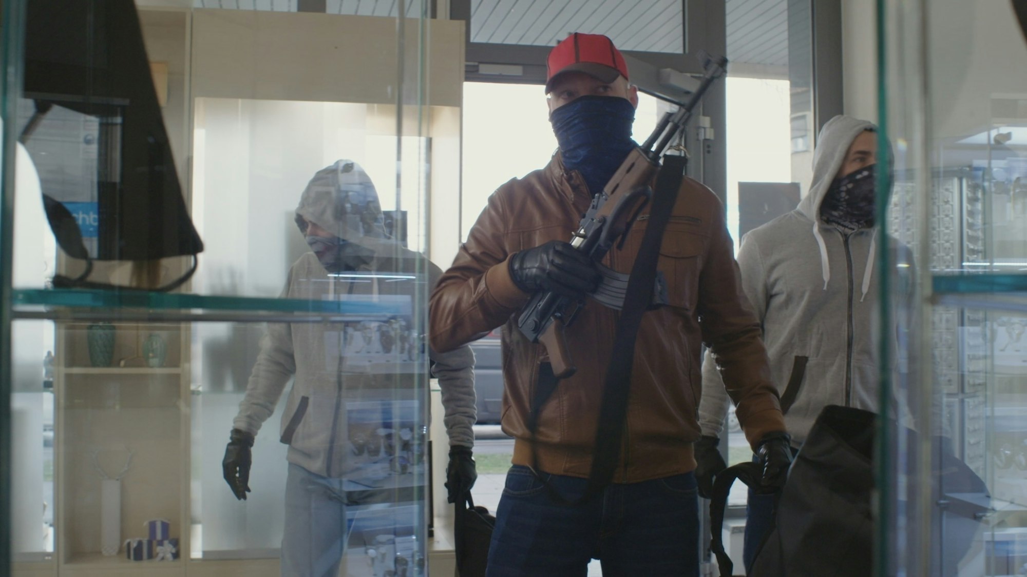 Drei vermummte Männer betreten ein Juweliergeschäft, einer ist mit einem Sturmgewehr bewaffnet.