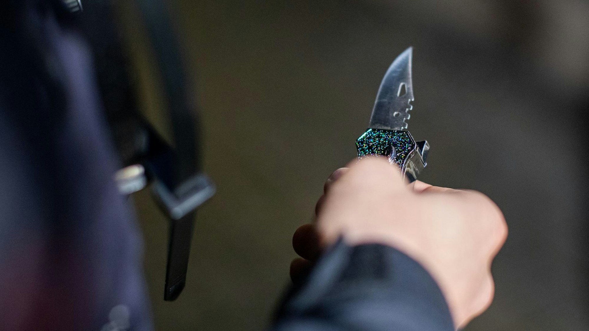Ein Mann hält ein aufgeklapptes Messer in der Hand.