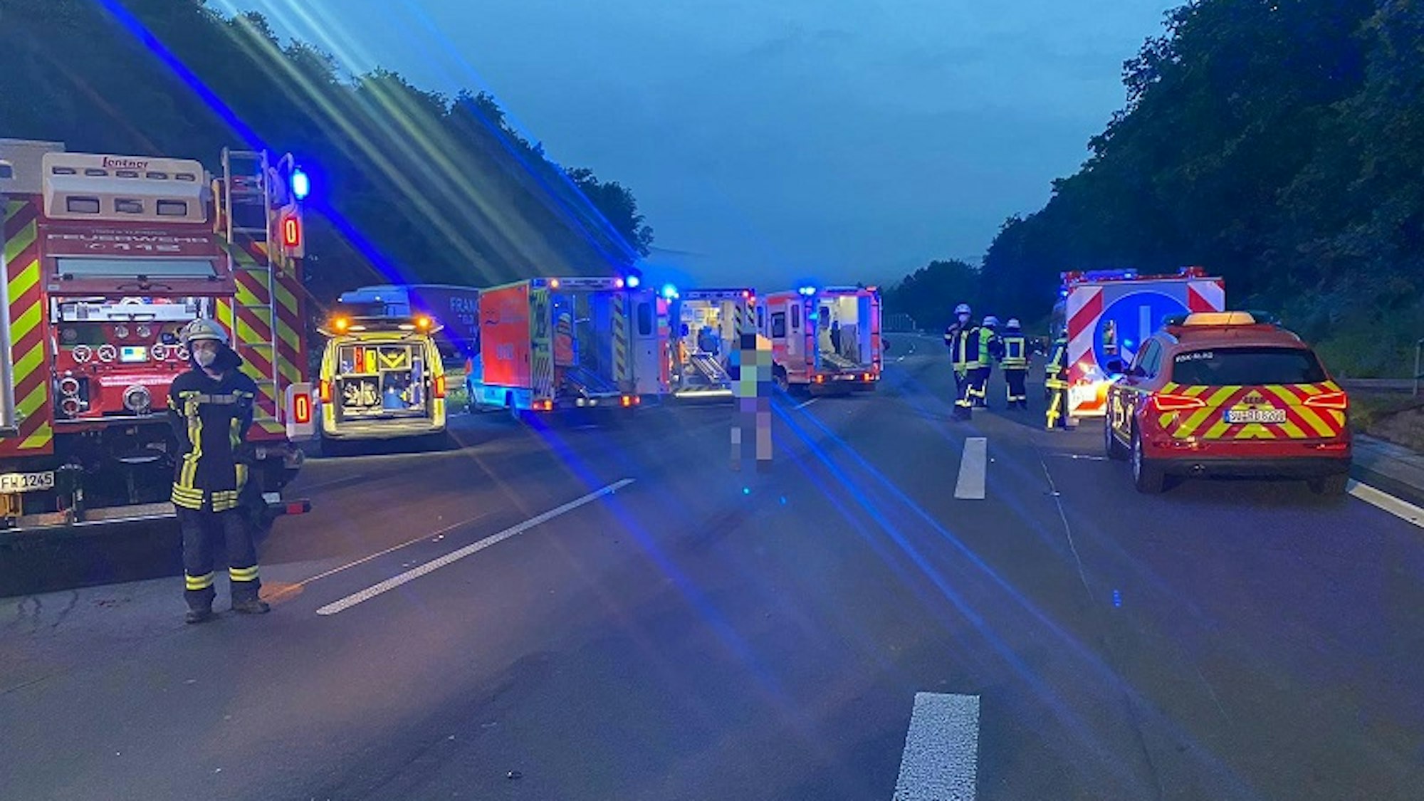 Einsatzkräfte der Feuerwehr stehen nach einem Unfall auf der A3.
