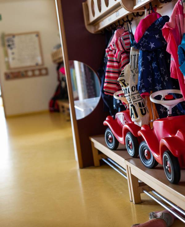 Die Garderobe einer Kita mit Jacken und Bobbycars