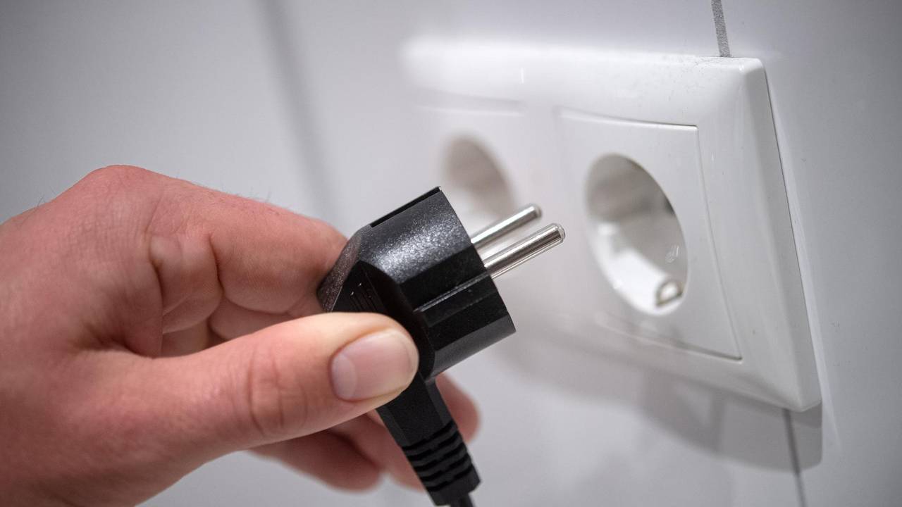 Eine Person will einen Stecker in die Steckdose stecken. In einigen Kölner Stadtteilen war das Mittwochnachmittag vergeblich, dort war der Strom weg.