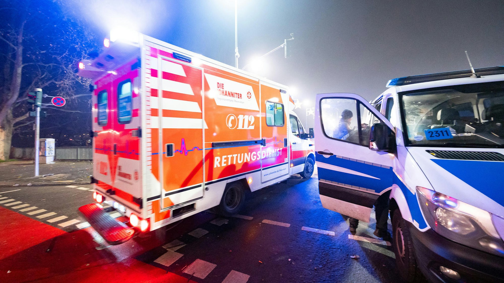 Ein Rettungswagen und ein Polizeifahrzeug stehen auf der Straße.