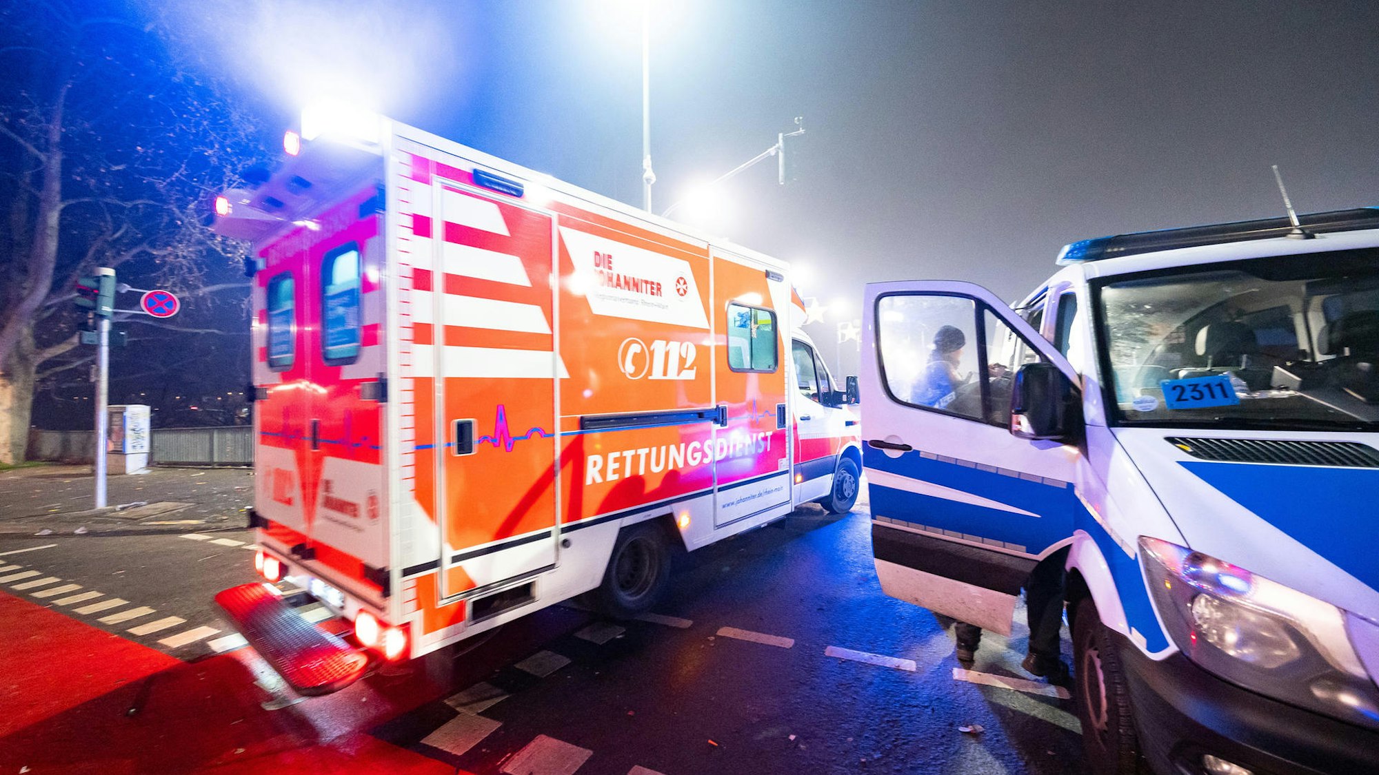 Ein Rettungswagen und ein Polizeiwagen stehen auf einer Kreuzung.