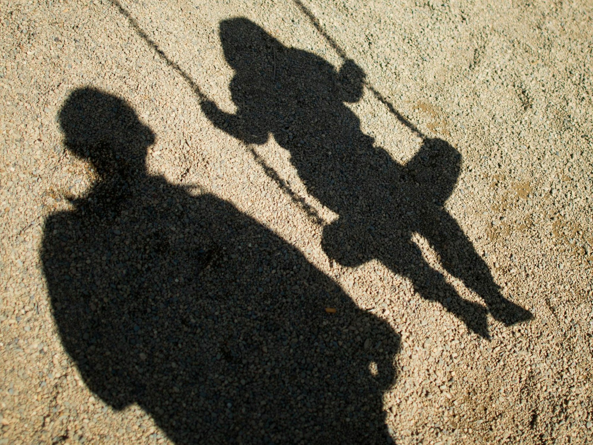 Ein Mann steht neben einem Kind, das auf einer Schaukel sitzt.