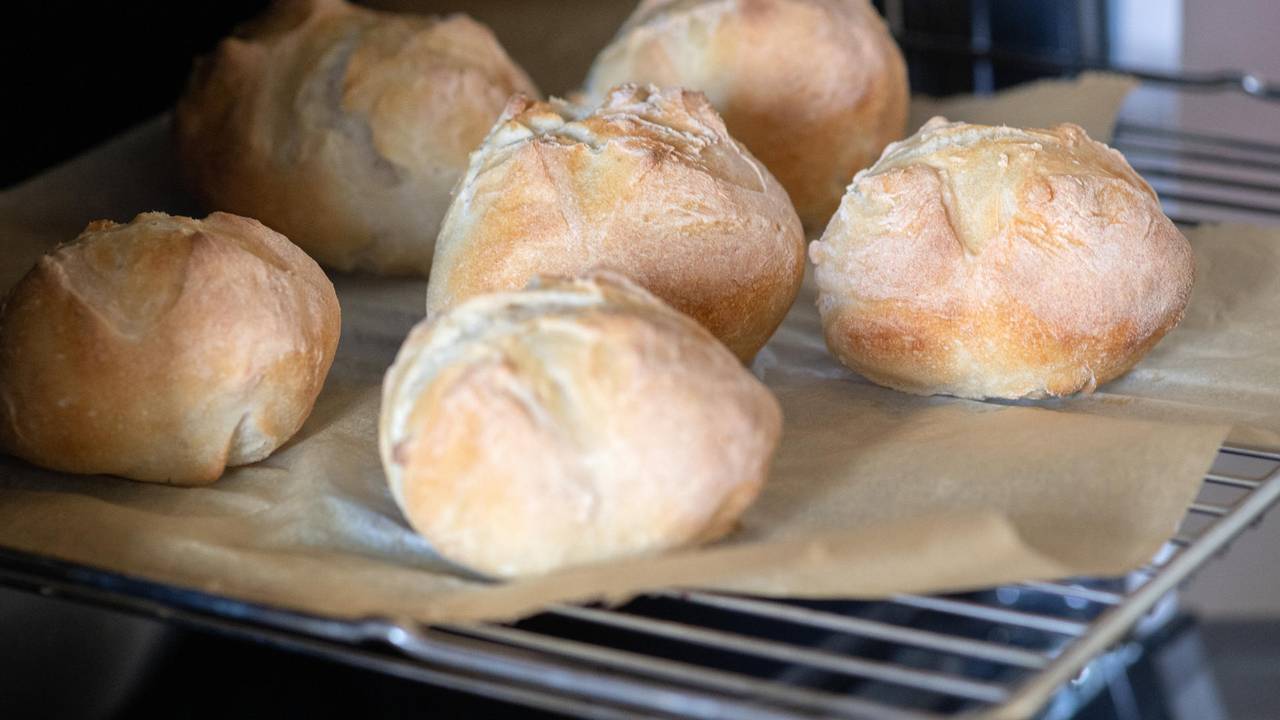 Das undatierte Symbolfoto zeigt sechs Aufbackbrötchen, die mit Backpapier auf einem Gitterrost liegen.