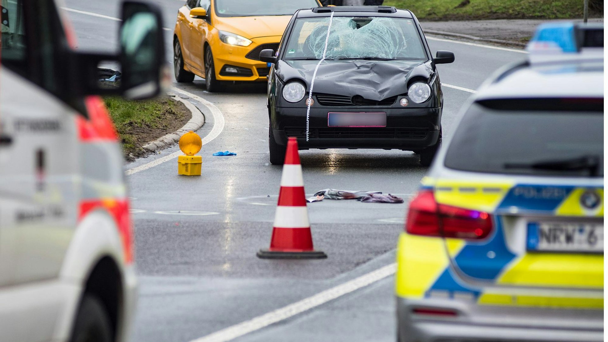 Polizei und Rettungsdienst sind auf einer Straße zu sehen.