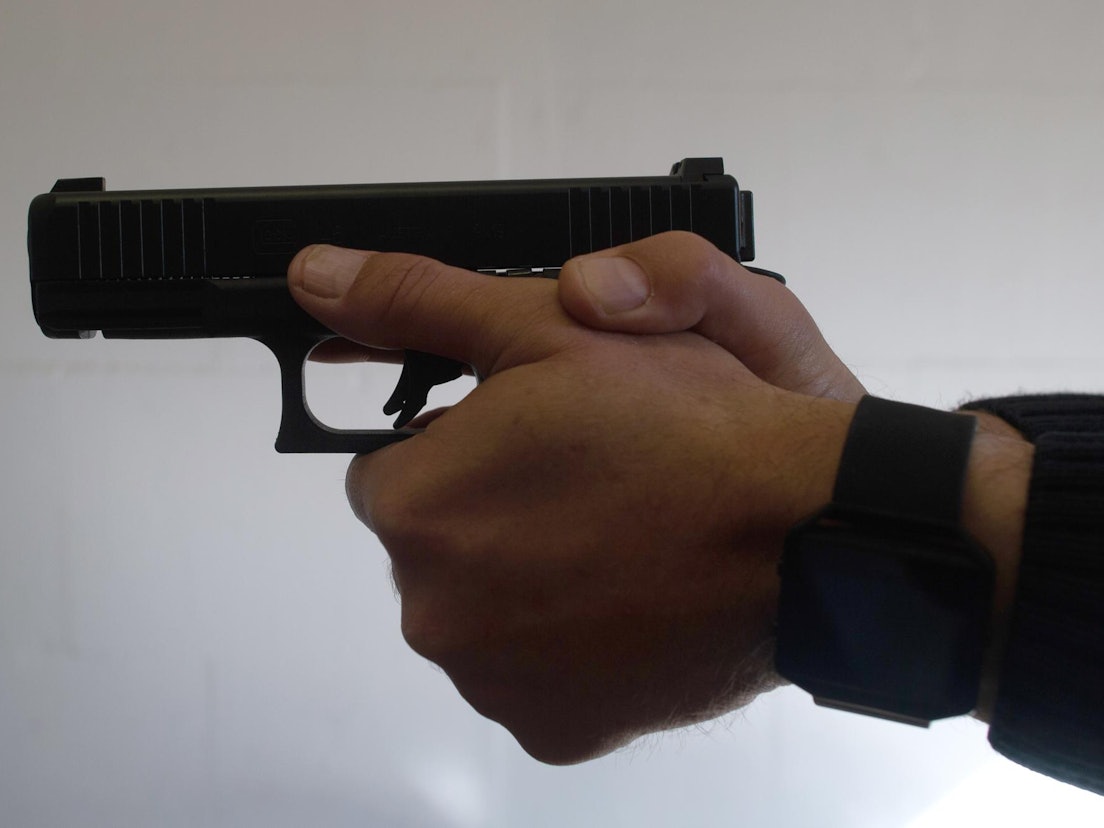 Ein Mann hält eine Pistole in beiden Händen.