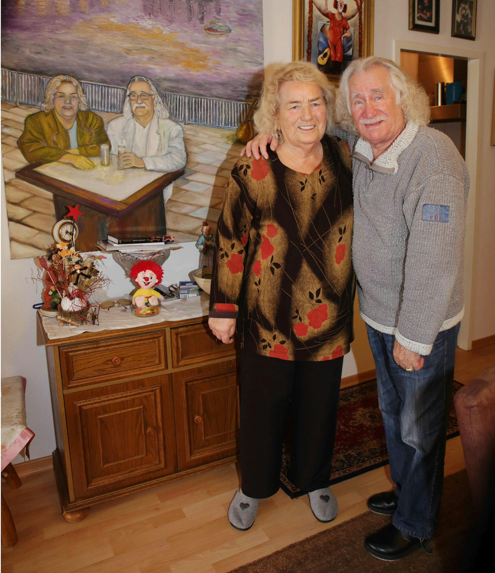 Hans Süper und Helga Süper stehen Arm in Arm im Wohnzimmer.