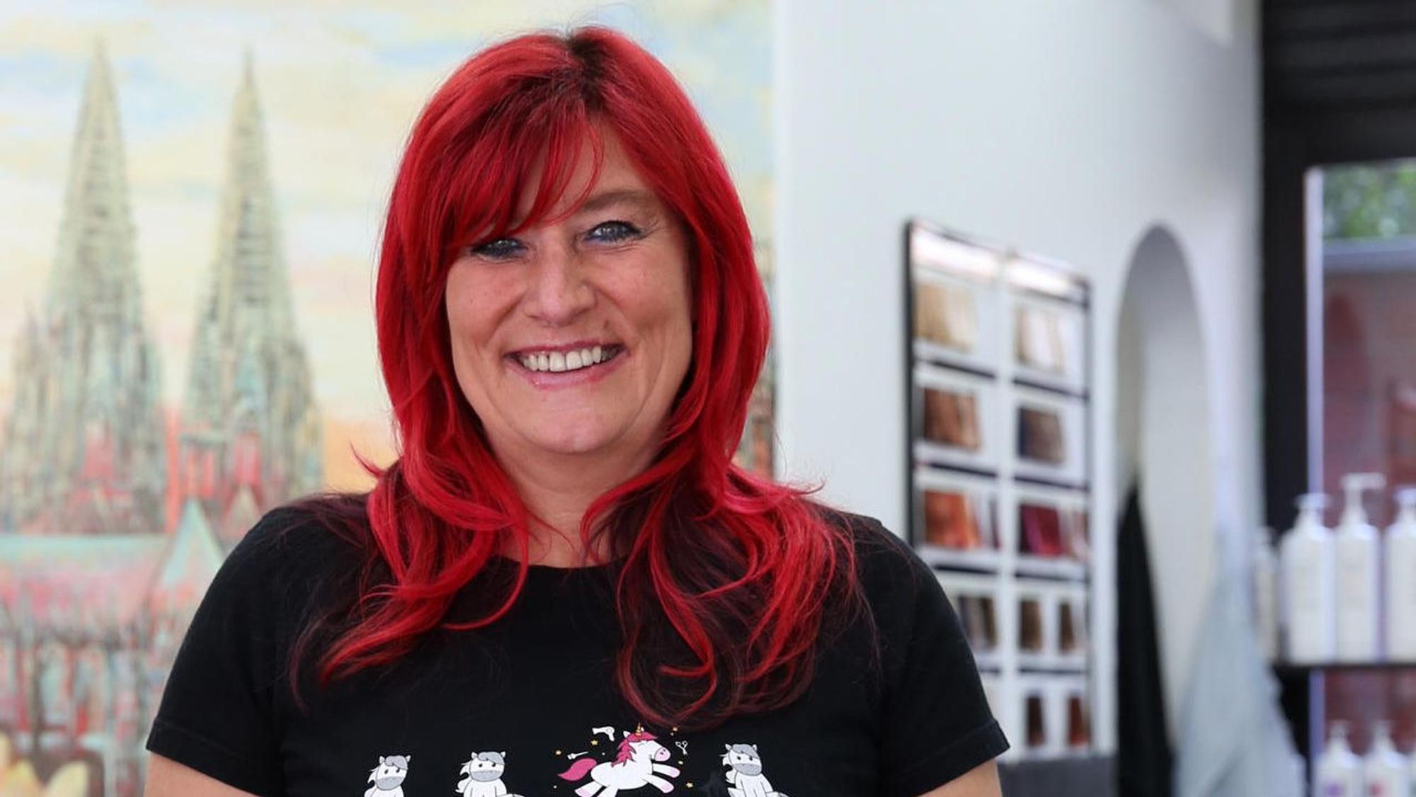 Kölner Friseurin Heike Beckmann-Kuckhoff steht in ihrem Salon und schaut in die Kamera.