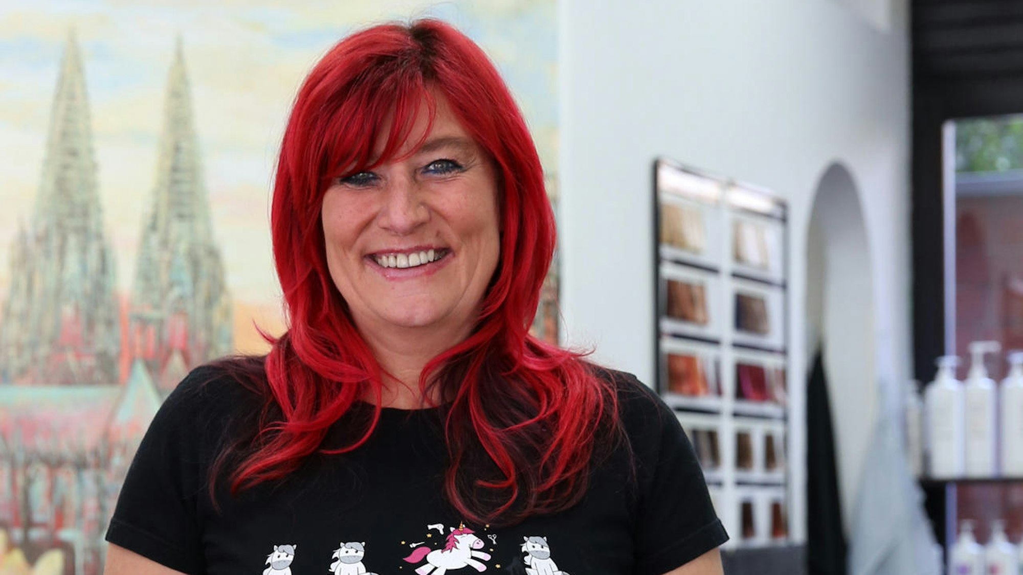 Kölner Friseurin Heike Beckmann-Kuckhoff steht in ihrem Salon und schaut in die Kamera.