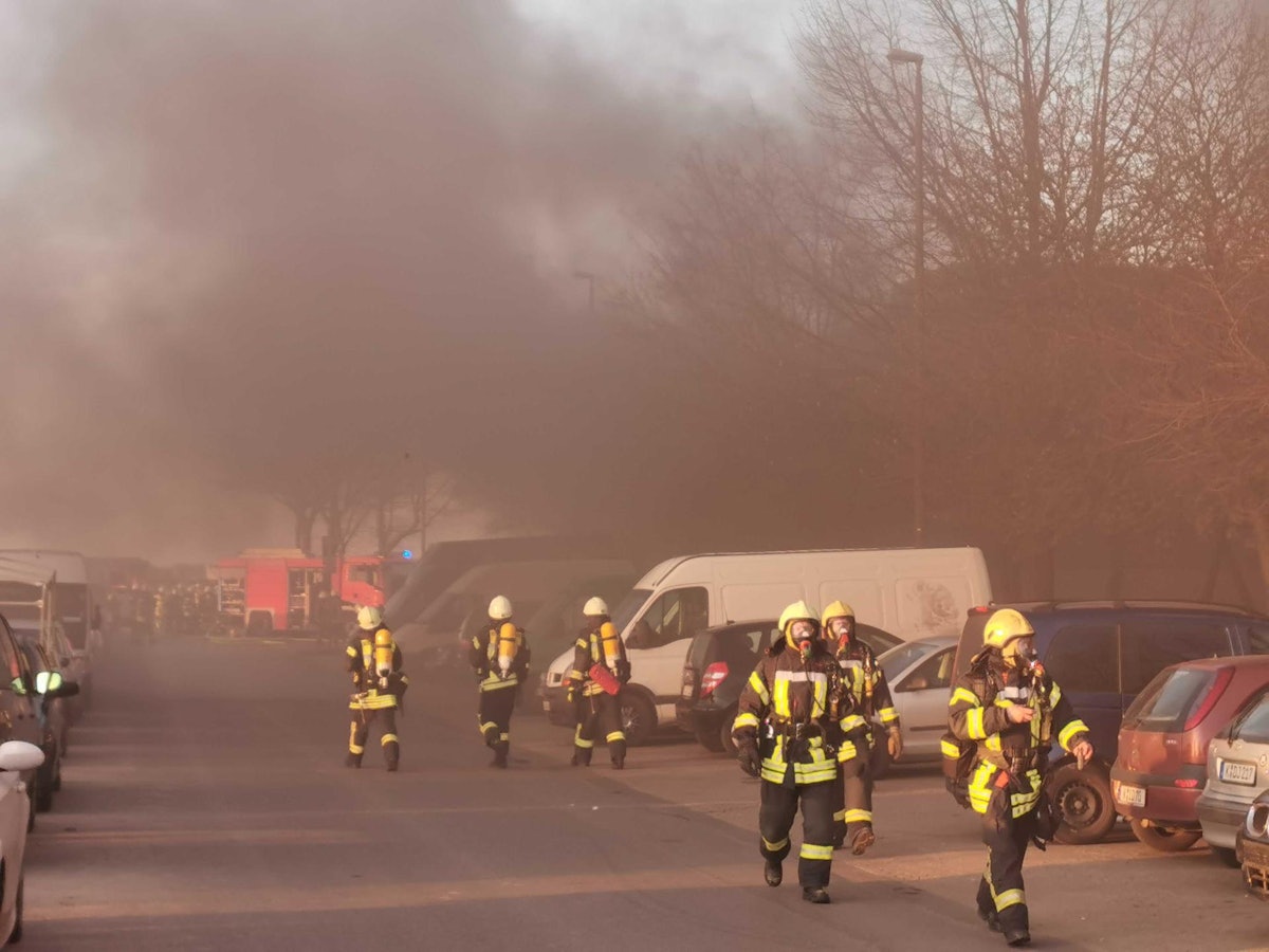 Feuerwehrleute im Einsatz, im Hintergrund starker Rauch.