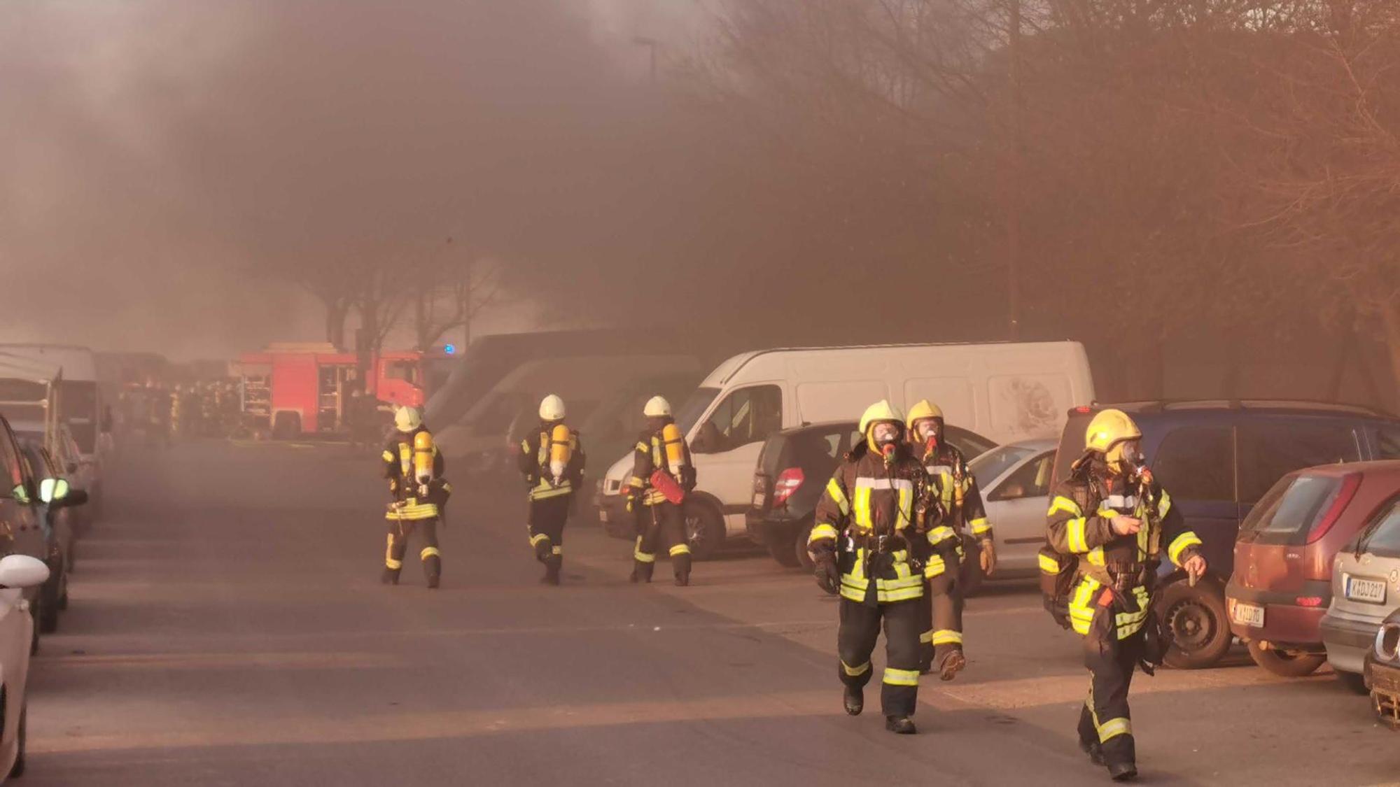 Feuerwehrleute im Einsatz, im Hintergrund starker Rauch.