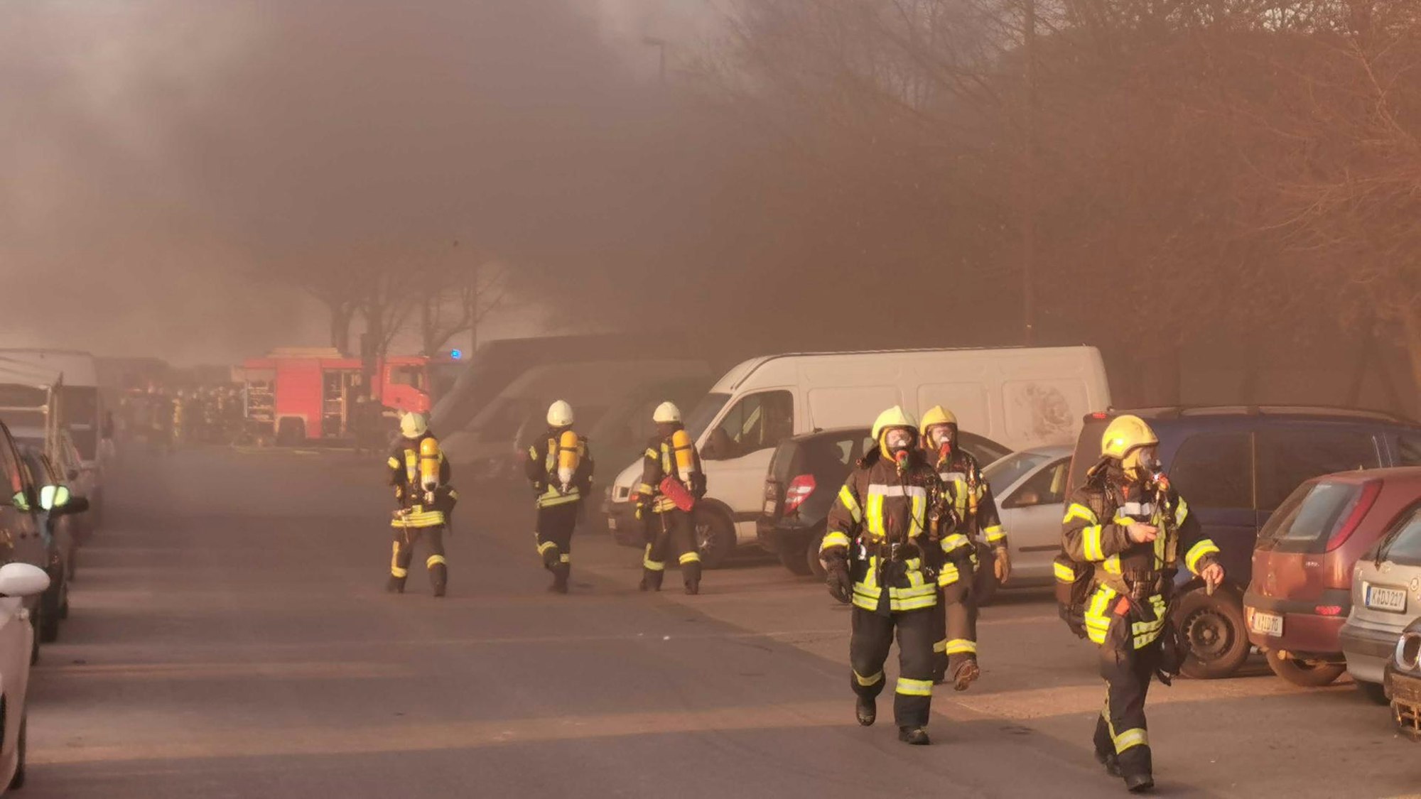 Feuerwehrleute im Einsatz, im Hintergrund starker Rauch.