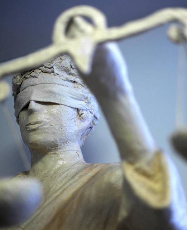 Eine Figur der Justitia steht in einem Gericht.