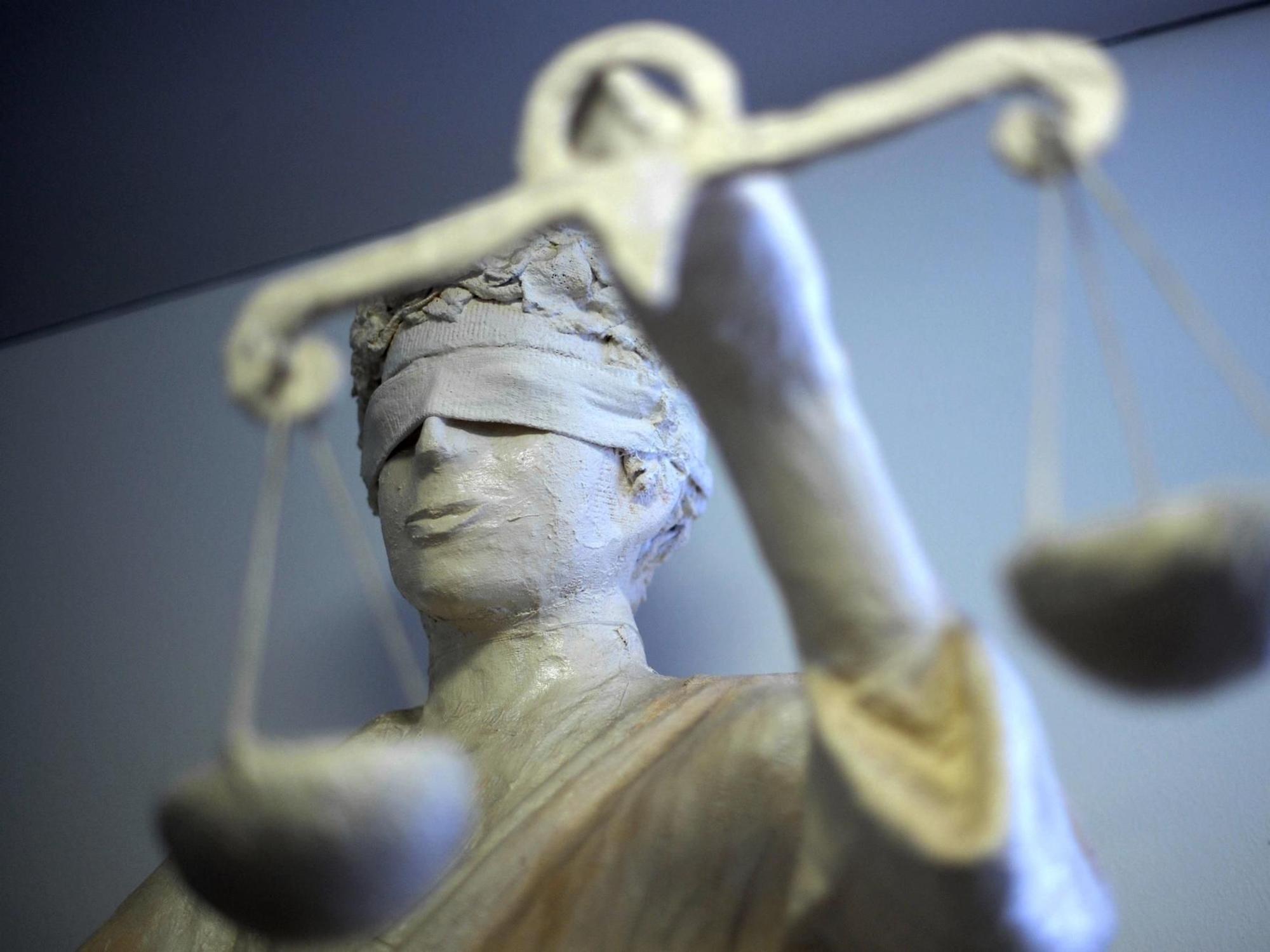 Eine Figur der Justitia steht in einem Gericht.