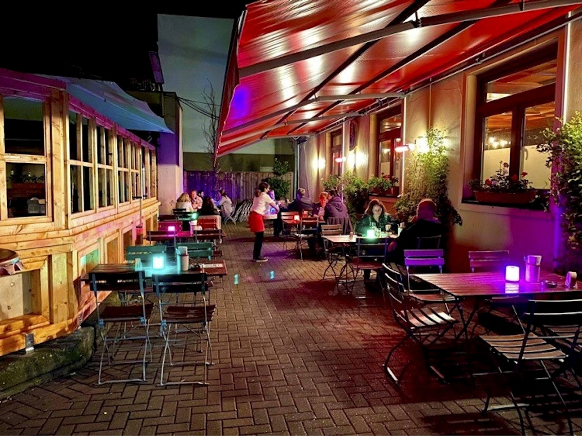 Gäste sitzen draußen im Haus Unkelbach an Tischen