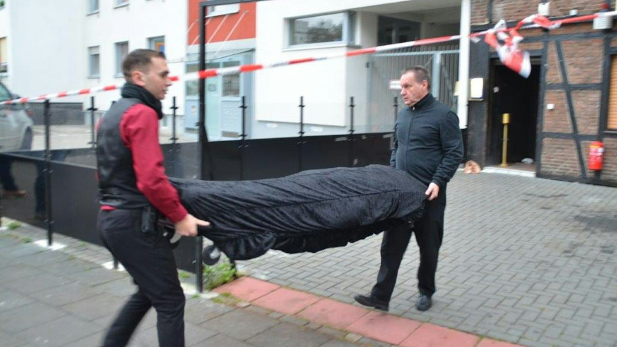 Bestatter tragen eine Leiche weg.