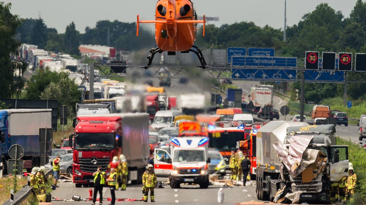 Ein Rettungshubschrauber fliegt zu einer Unfallstelle auf einer Autobahn. Dort stehen zwei beschädigte Lkw, daneben steht ein Rettungswagen, zahlreiche Einsatzkräfte befinden sich auf der Fahrbahn.