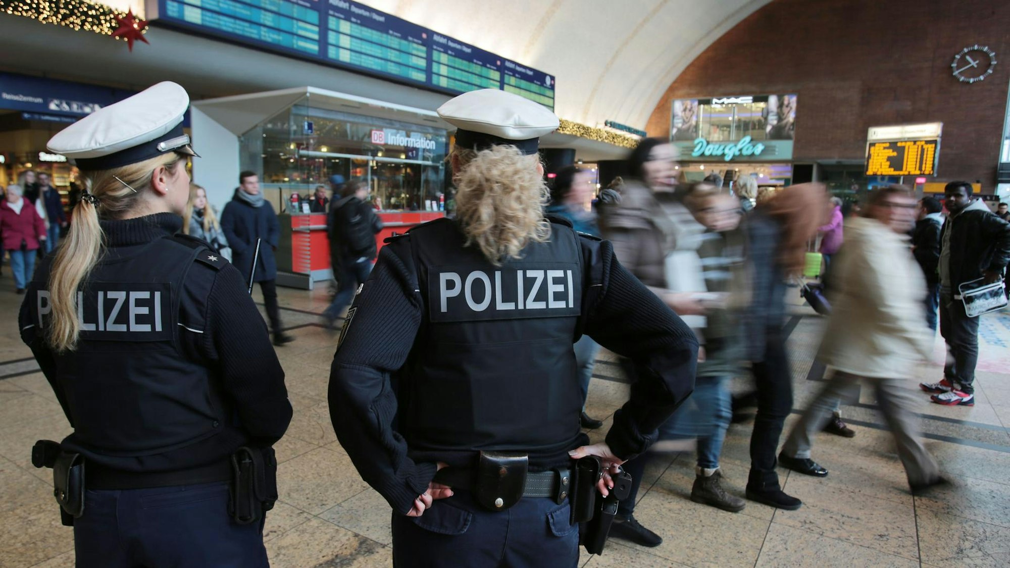 Polizistinnen kontrollieren im Kölner Hauptbahnhof Menschen.