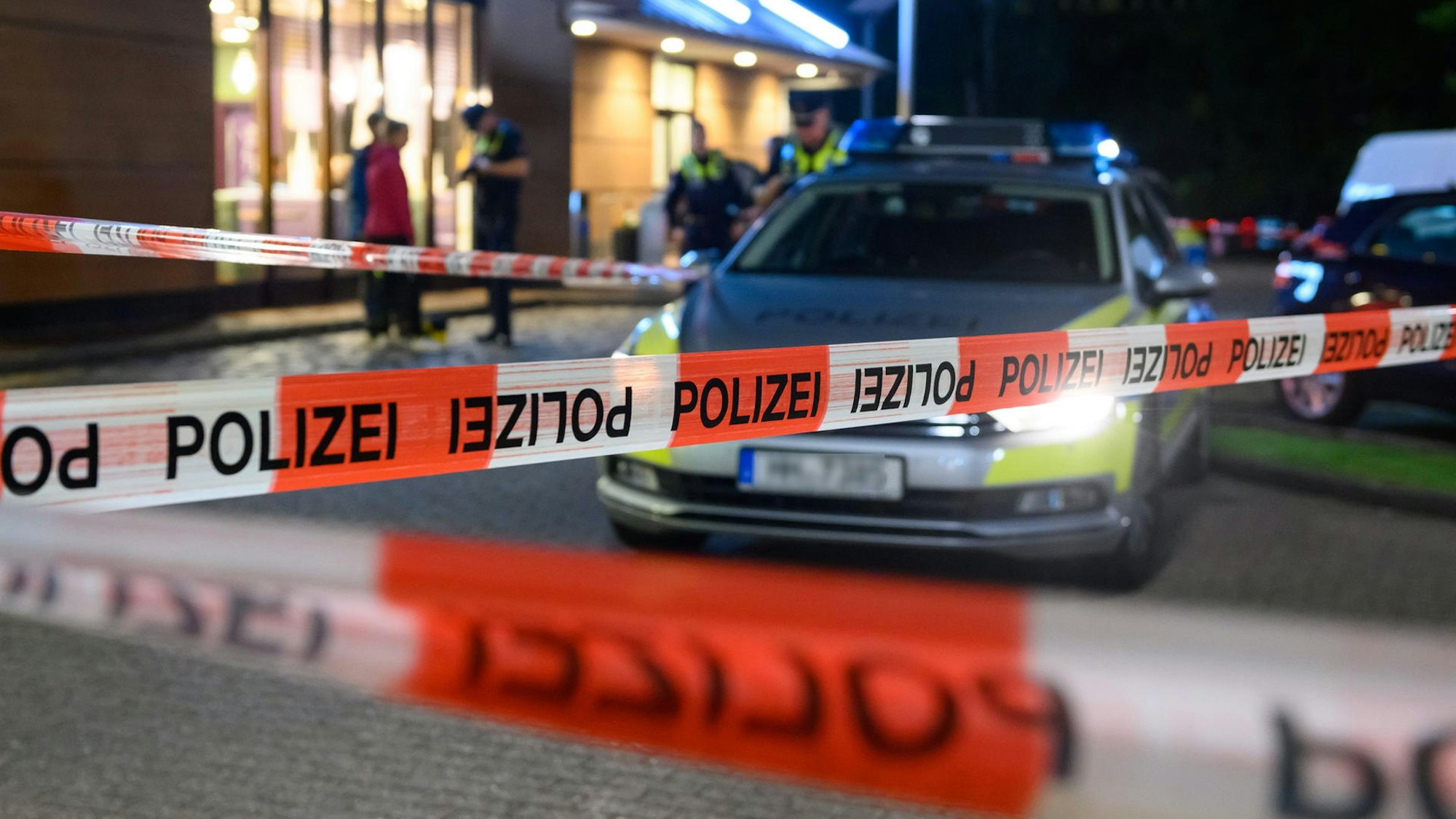 Ein Polizeiwagen steht hinter einer Absperrung.
