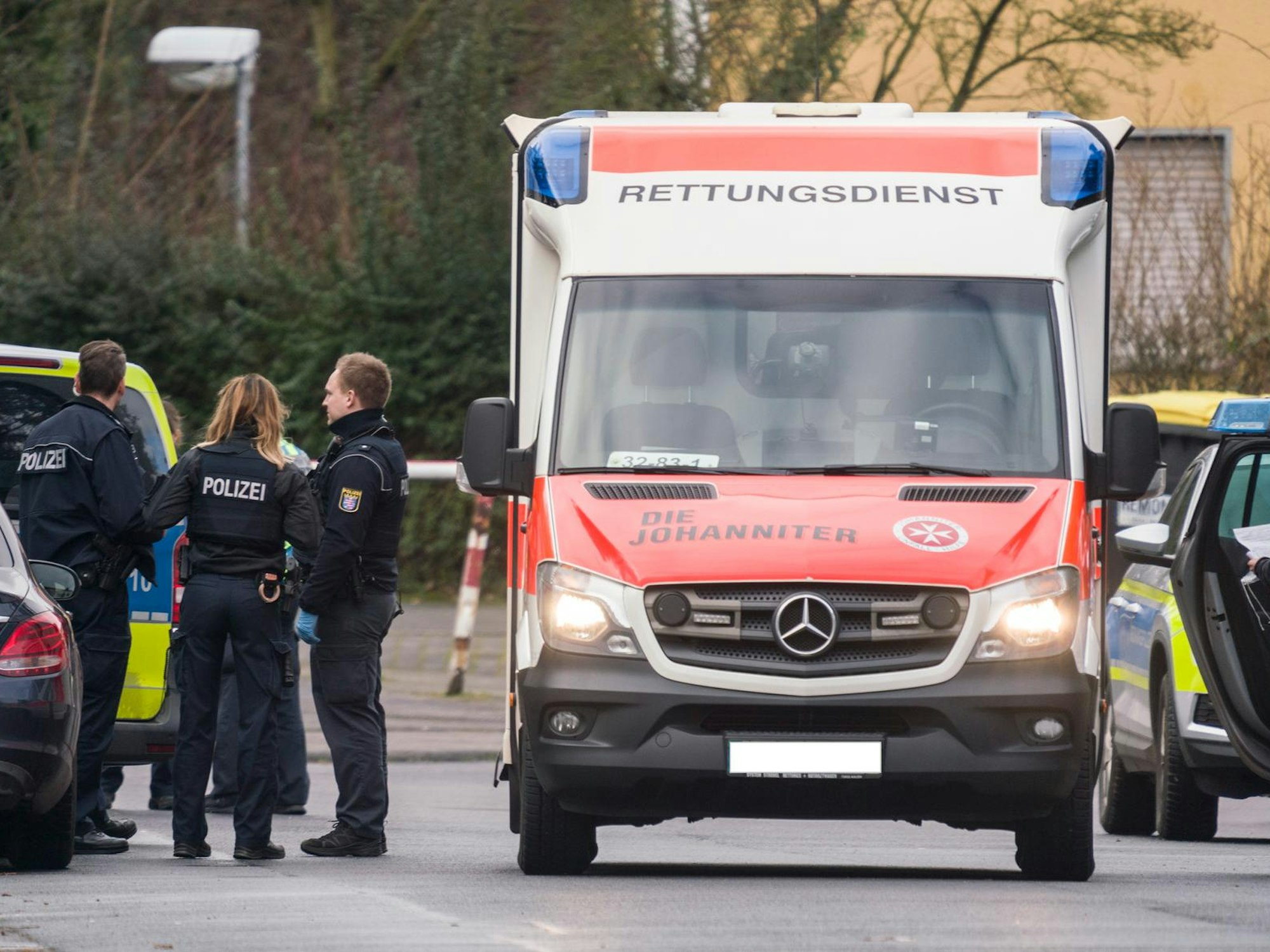 Einsatzkräfte der Polizei stehen neben einem Rettungswagen.