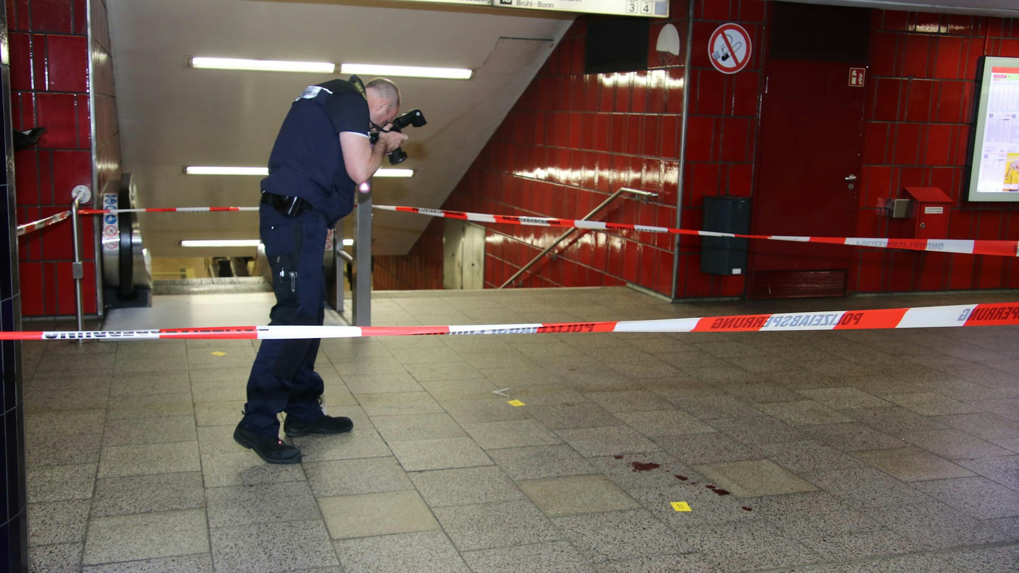 Ein Polizist fotografiert Blutspuren auf dem Boden.