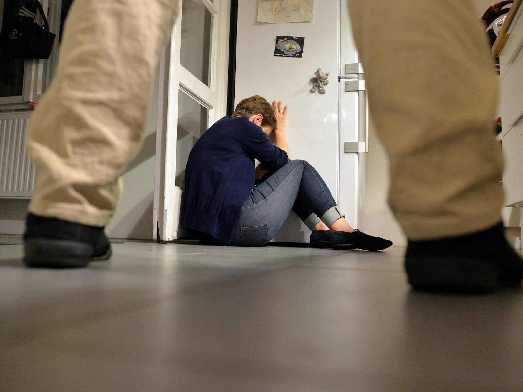 Eine Frau sitzt auf dem Boden und verdeckt ihr Gesicht.