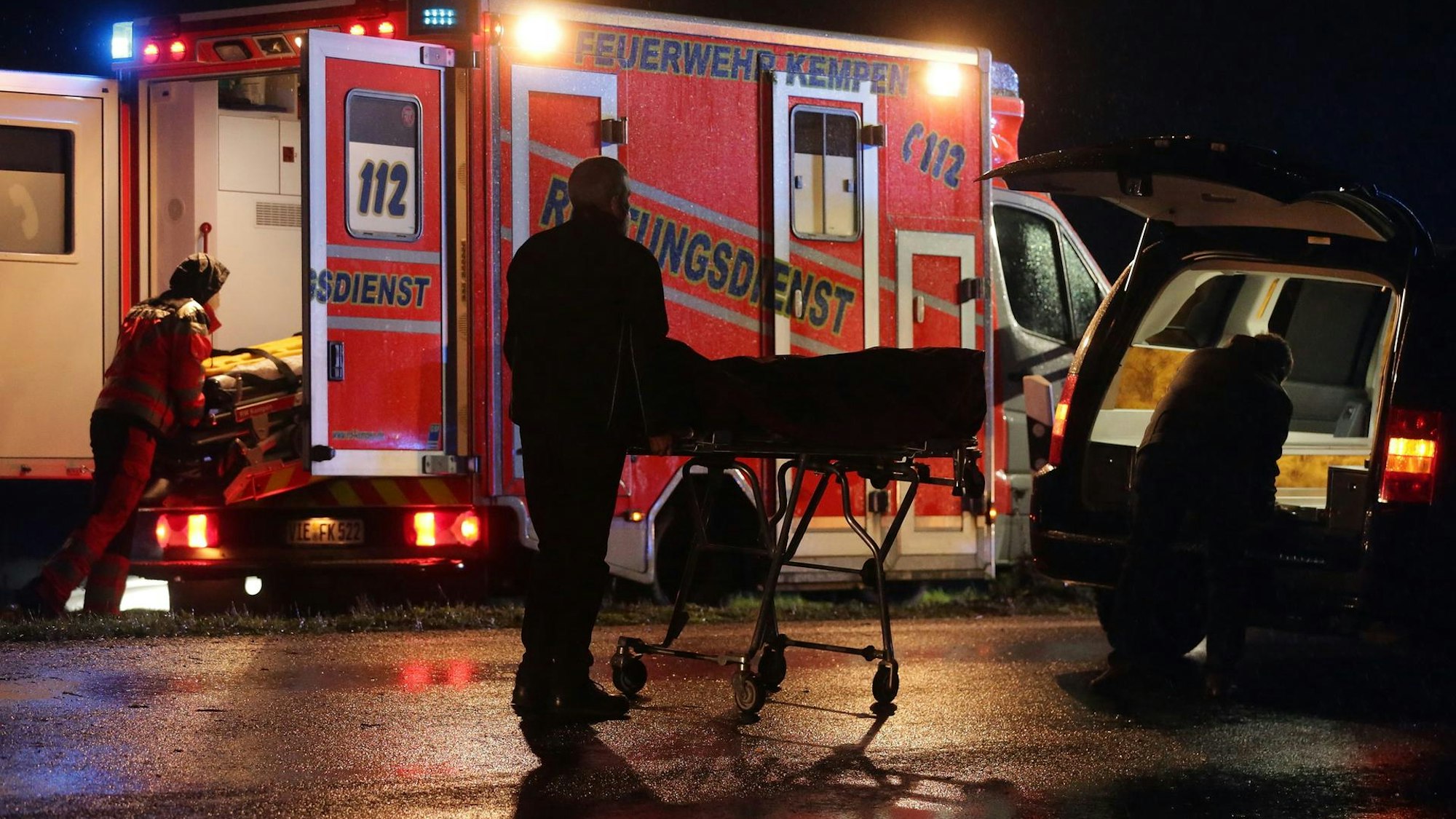 Bestatter bringen das Opfer in einen Leichenwagen.