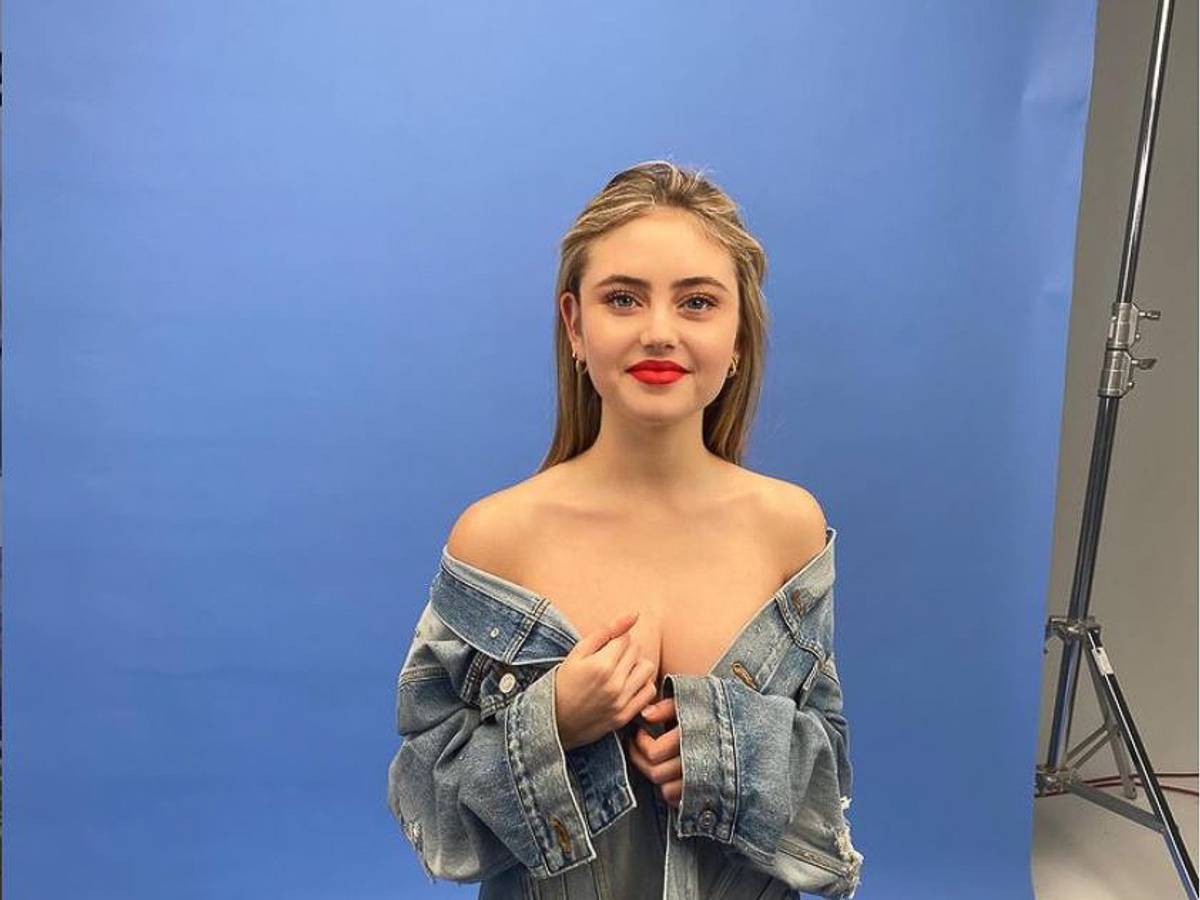 Leni Klum bei einem Fotoshooting schulterfrei mit einer Jeans-Jacke vor einer blauen Wand
