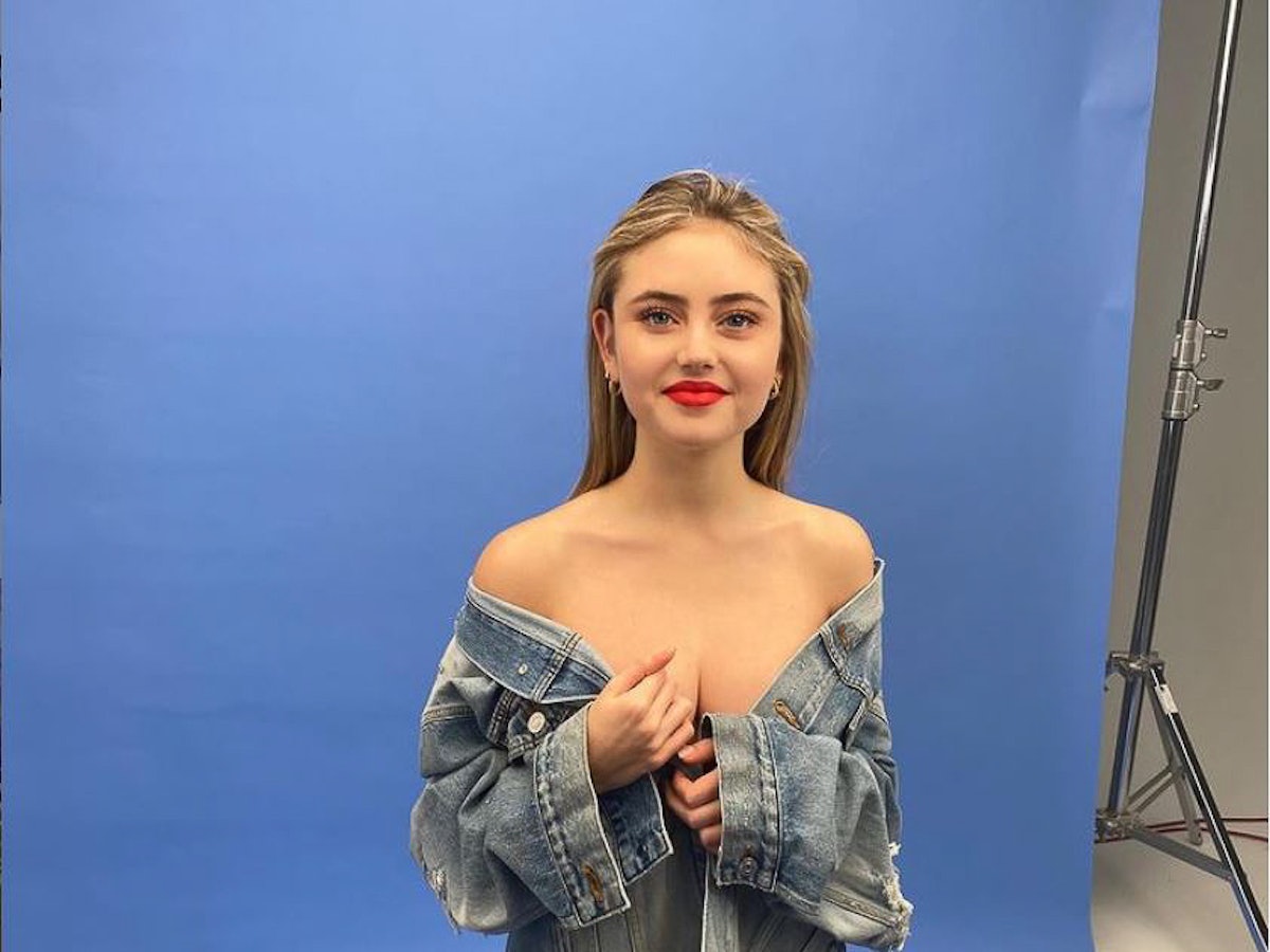 Leni Klum bei einem Fotoshooting schulterfrei mit einer Jeans-Jacke vor einer blauen Wand