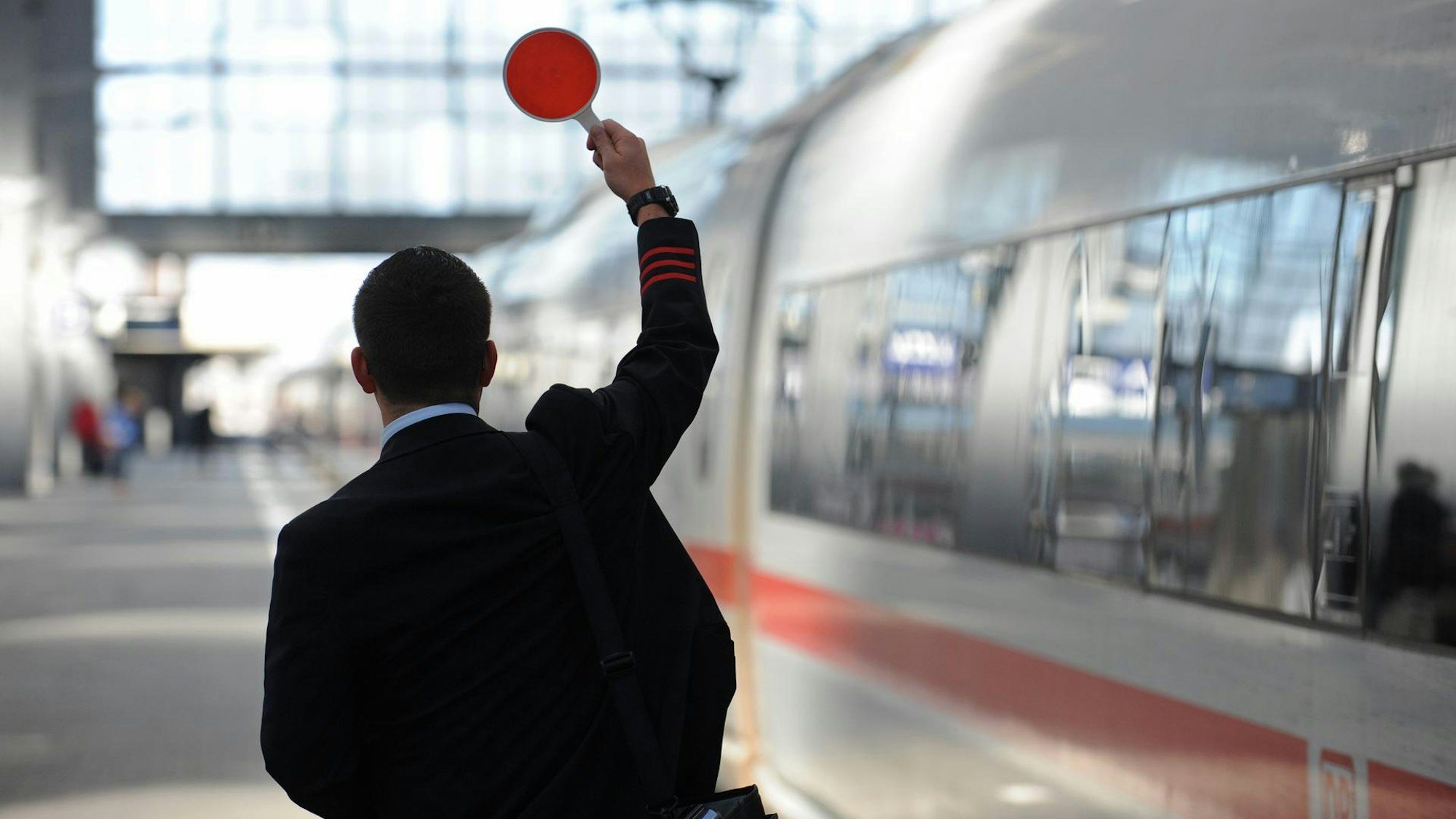 Kölner Hauptbahnhof: Zugbegleiter steht am Bahnsteig.