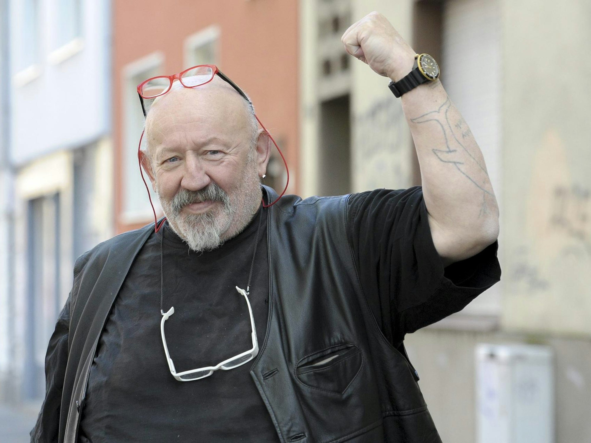 Jürgen Zeltinger reckt die Faust in die Höhe und lächelt in die Kamera.