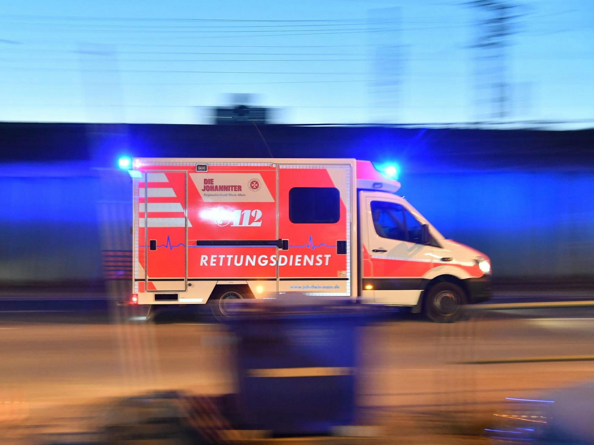 Ein Krankenwagen fährt mit Blaulicht auf einer Straße.
