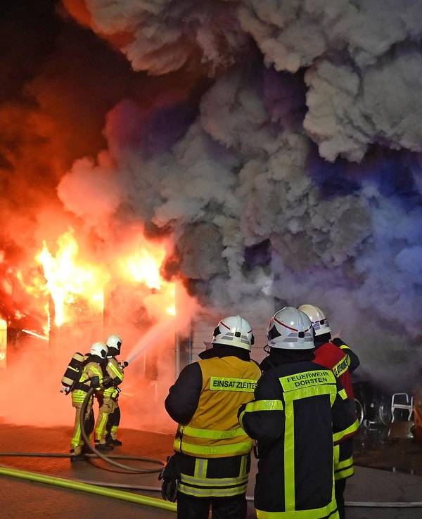 Feuerwehrleute löschen ein Gebäude, das lichterloh brennt.