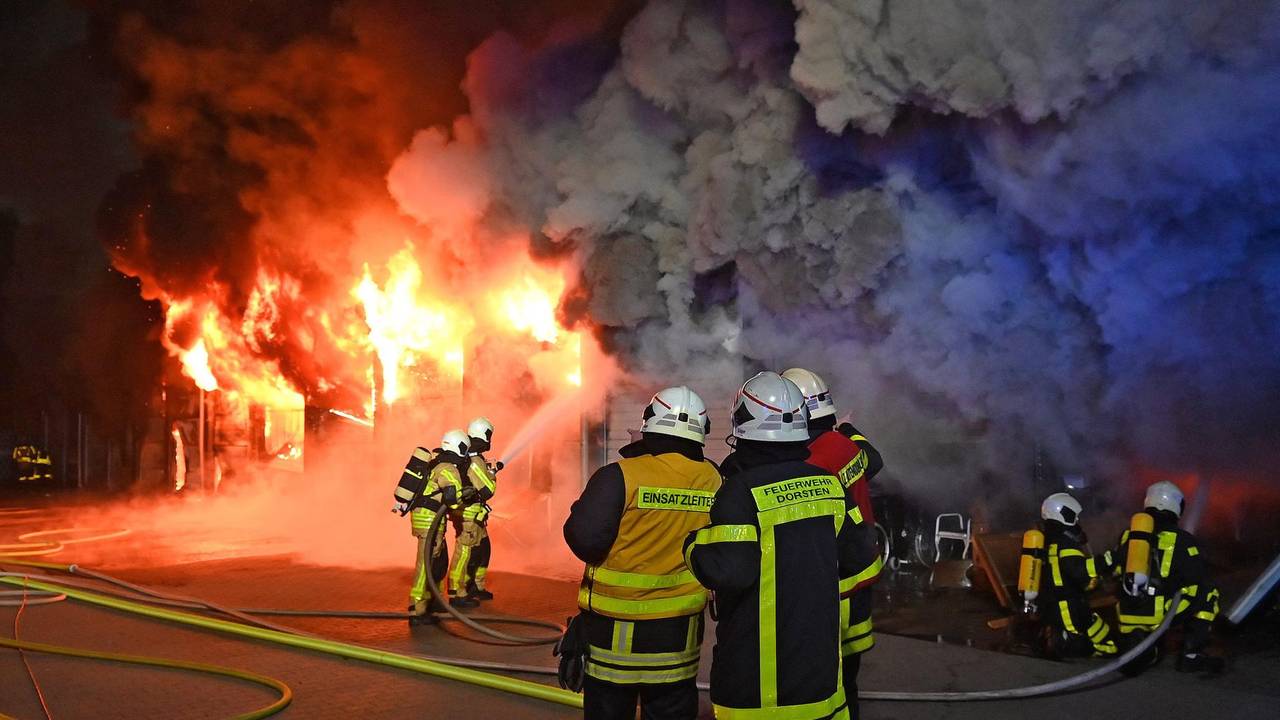 Feuerwehrleute löschen ein Gebäude, das lichterloh brennt.