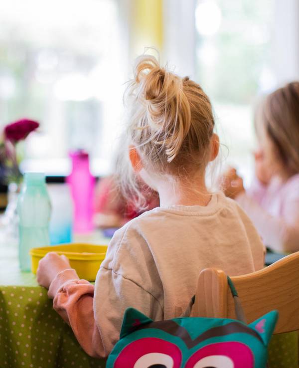 Kinder sitzen in einer Kita-Notbetreuung in NRW zusammen am Tisch.