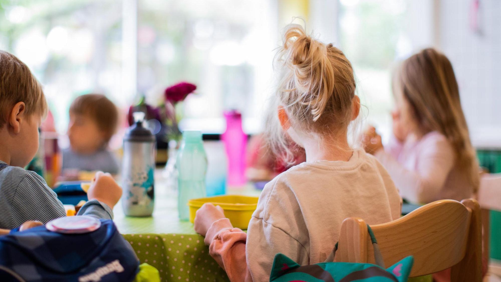 Kinder sitzen in einer Kita-Notbetreuung in NRW zusammen am Tisch.