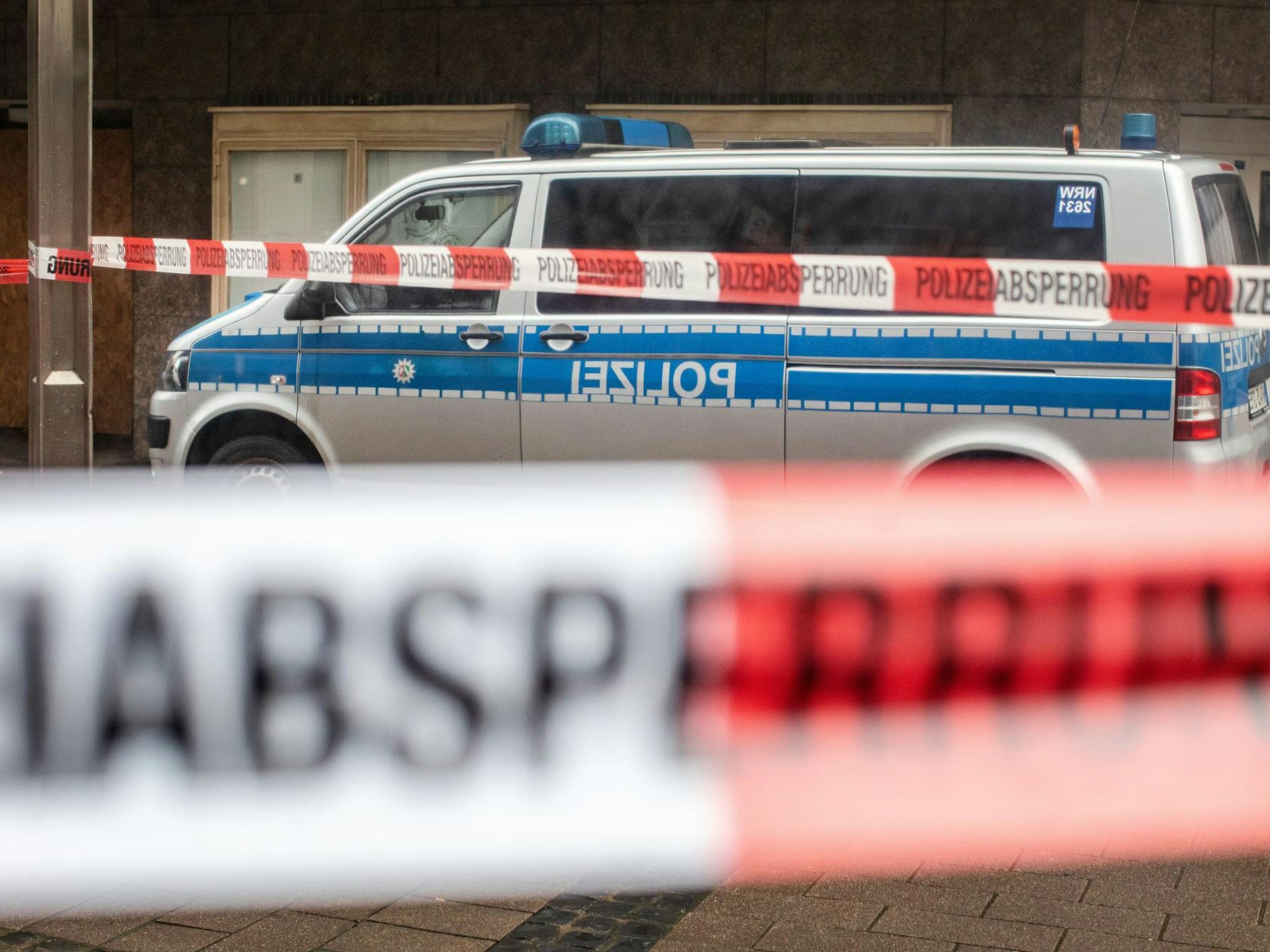 Ein Streifenwagen steht hinter einer Polizeiabsperrung.