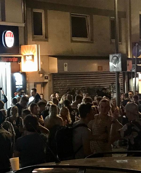 Viele Leute stehen dicht gedrängt vor einem Kiosk und anderen Lokalen an der Zülpicher Straße, Ecke Zülpicher Platz