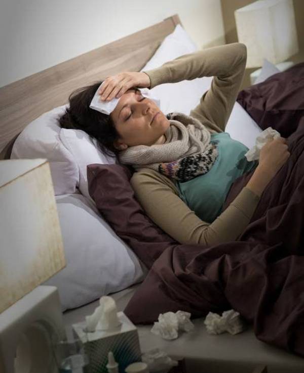 Eine Frau liegt krank im Bett.