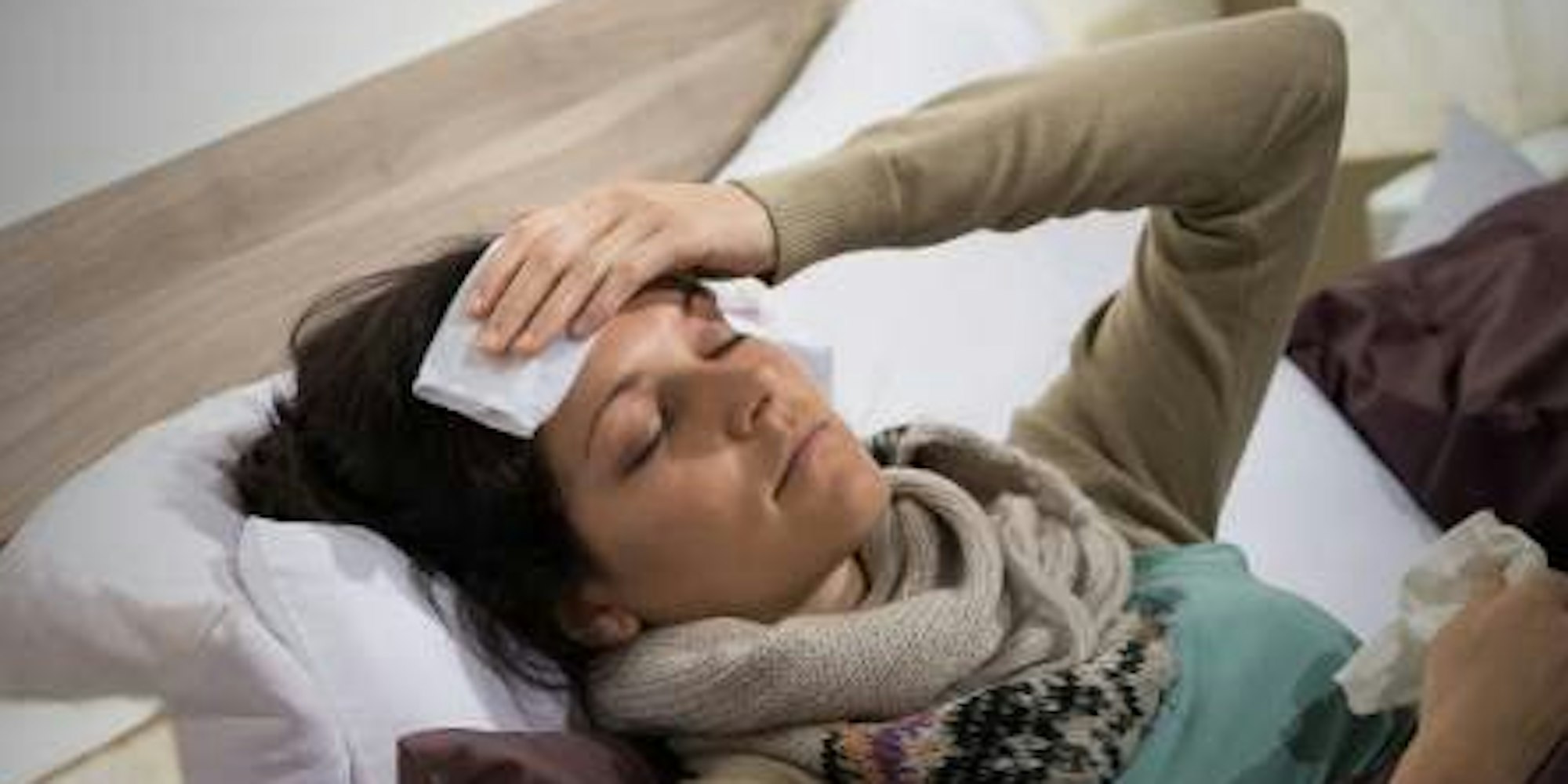 Eine Frau liegt krank im Bett.