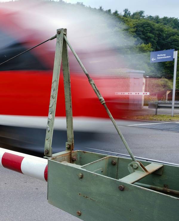 Ein Zug fährt bei geschlossenen Schranken vorbei
