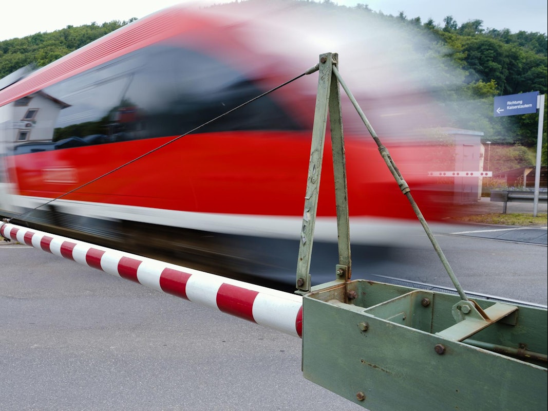 Ein Zug fährt bei geschlossenen Schranken vorbei