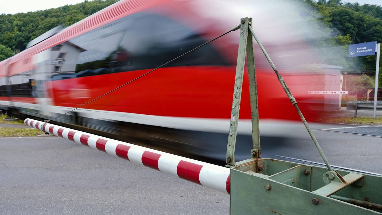 Ein Zug fährt bei geschlossenen Schranken vorbei