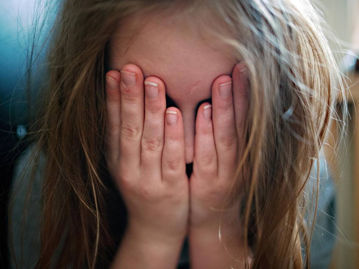 Ein Kind hält sich erschüttert die Hände vor das Gesicht.