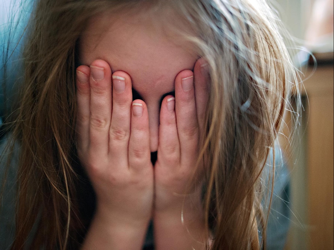 Ein Kind hält sich erschüttert die Hände vor das Gesicht.