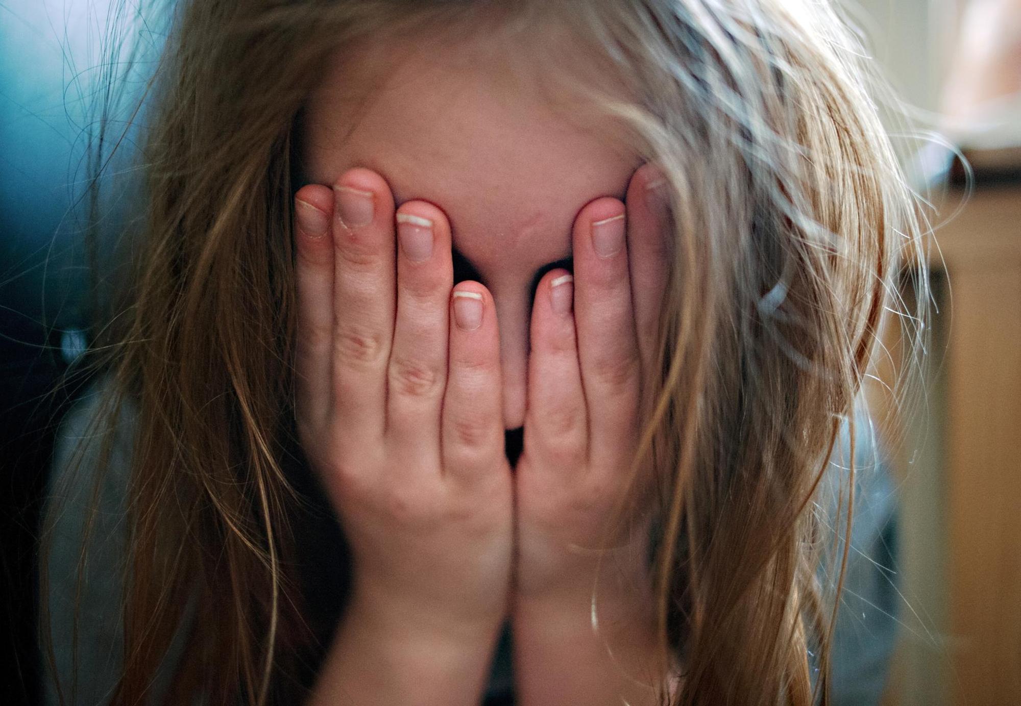 Ein Kind hält sich erschüttert die Hände vor das Gesicht.