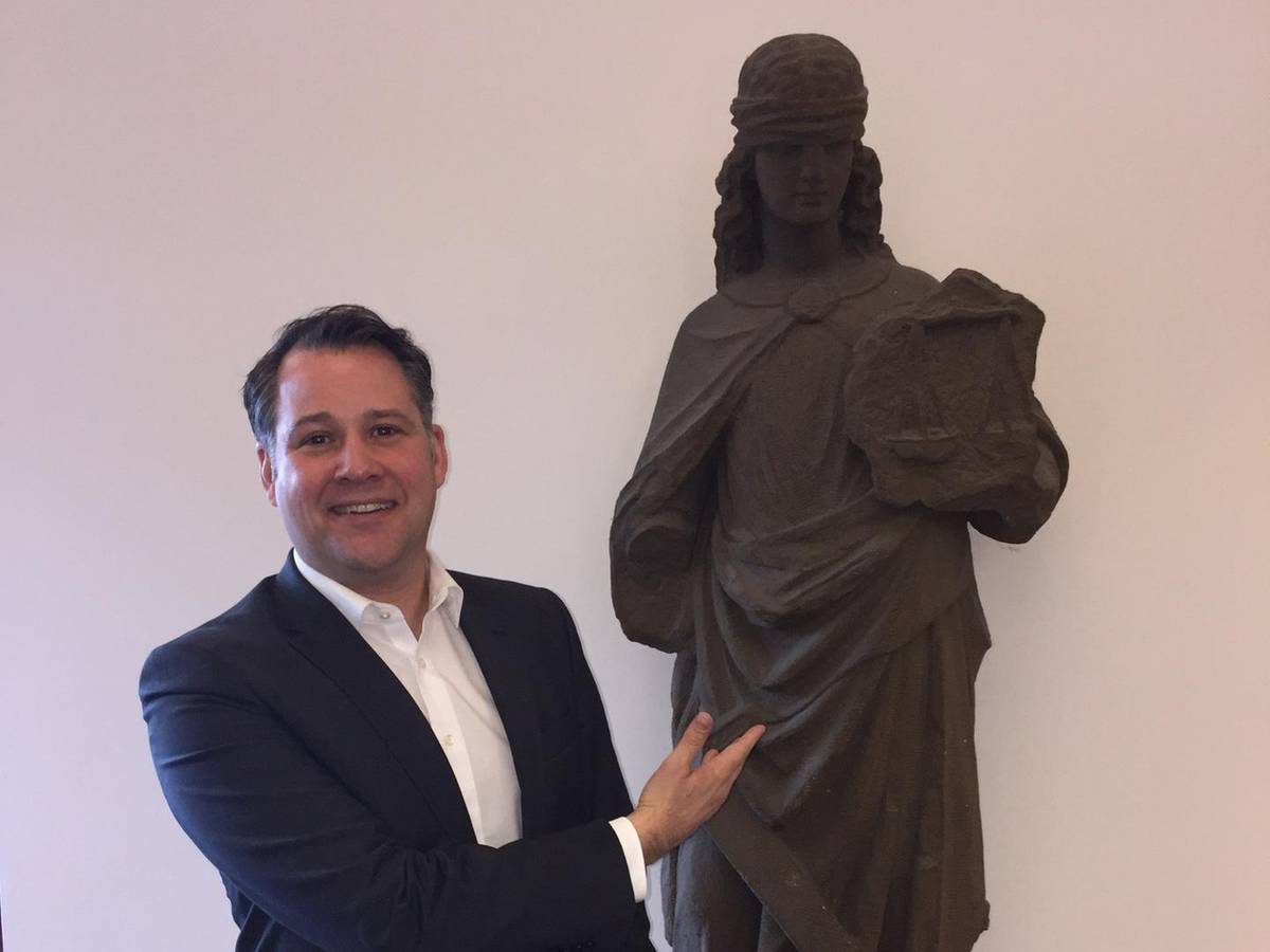 Jan F. Orth im Landgericht neben einer Statue der Justitia, der Göttin der Gerechtigkeit