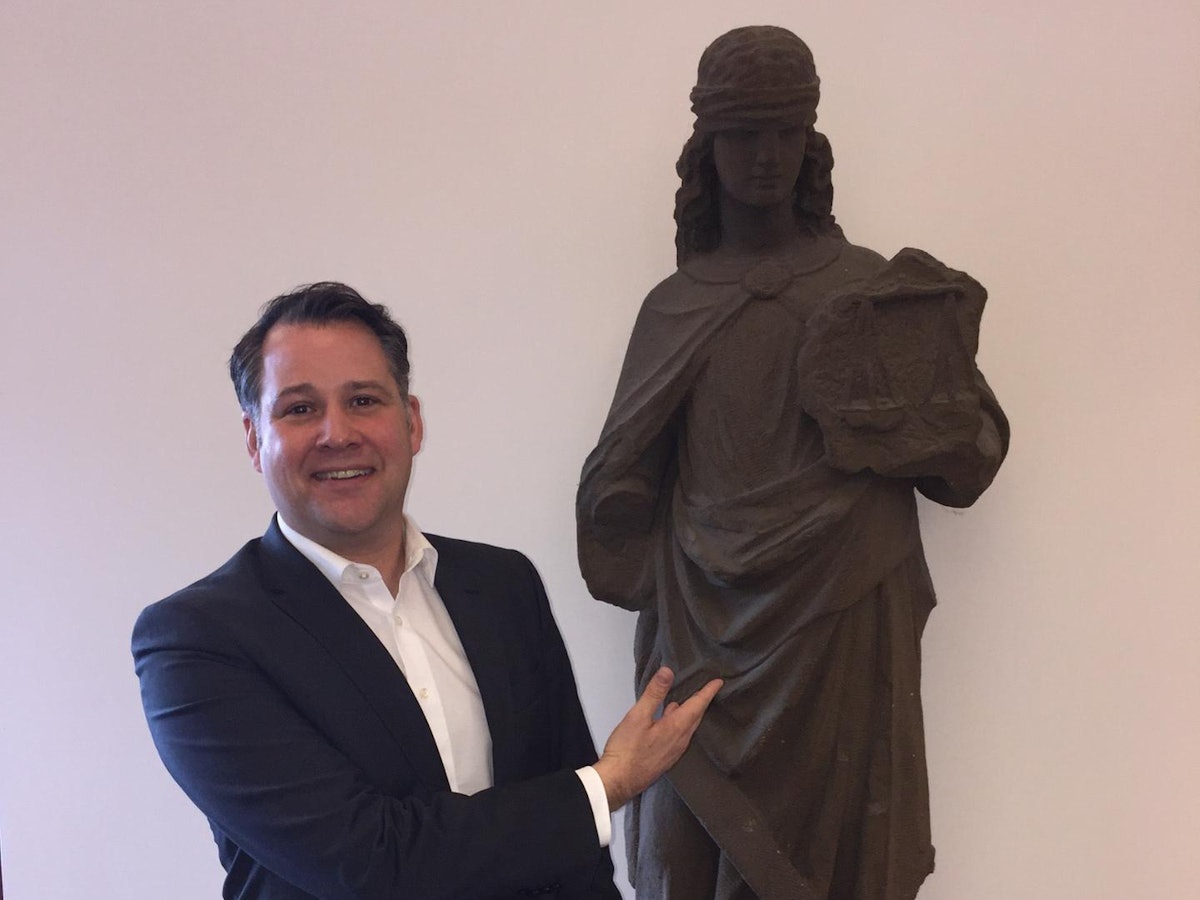 Jan F. Orth im Landgericht neben einer Statue der Justitia, der Göttin der Gerechtigkeit